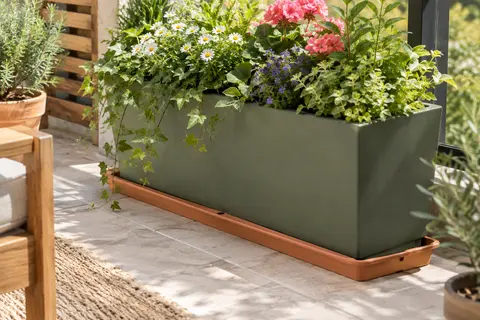 Soucoupe rectangulaire en plastique terracotta sous une jardinière fleurie sur un balcon lumineux