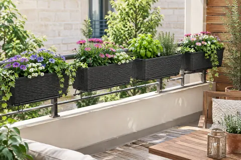 Quatre jardinières anthracite à aspect rotin, garnies de fleurs et suspendues à une rambarde de balcon.