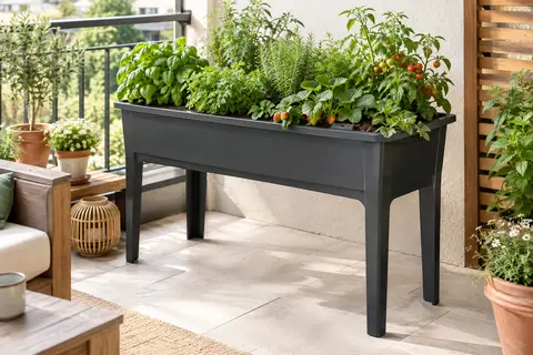 Table potagère anthracite sur un balcon, garnie d’aromates dans un bac surélevé.