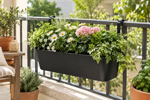 Jardinière suspendue en métal noir à crochets, garnie de fleurs sur la rambarde d’un balcon lumineux.