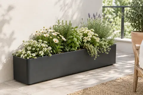 Jardinière rectangulaire anthracite en fibre de verre, garnie de fleurs et d’aromates sur un balcon lumineux